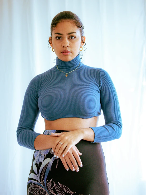 a woman is posing in a black skirt and blue shirt
