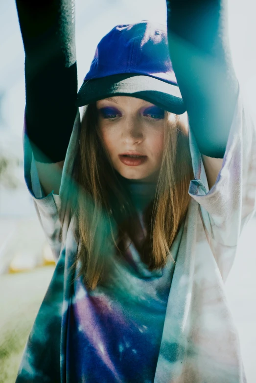 a woman is wearing a tie - dyed shirt and hat