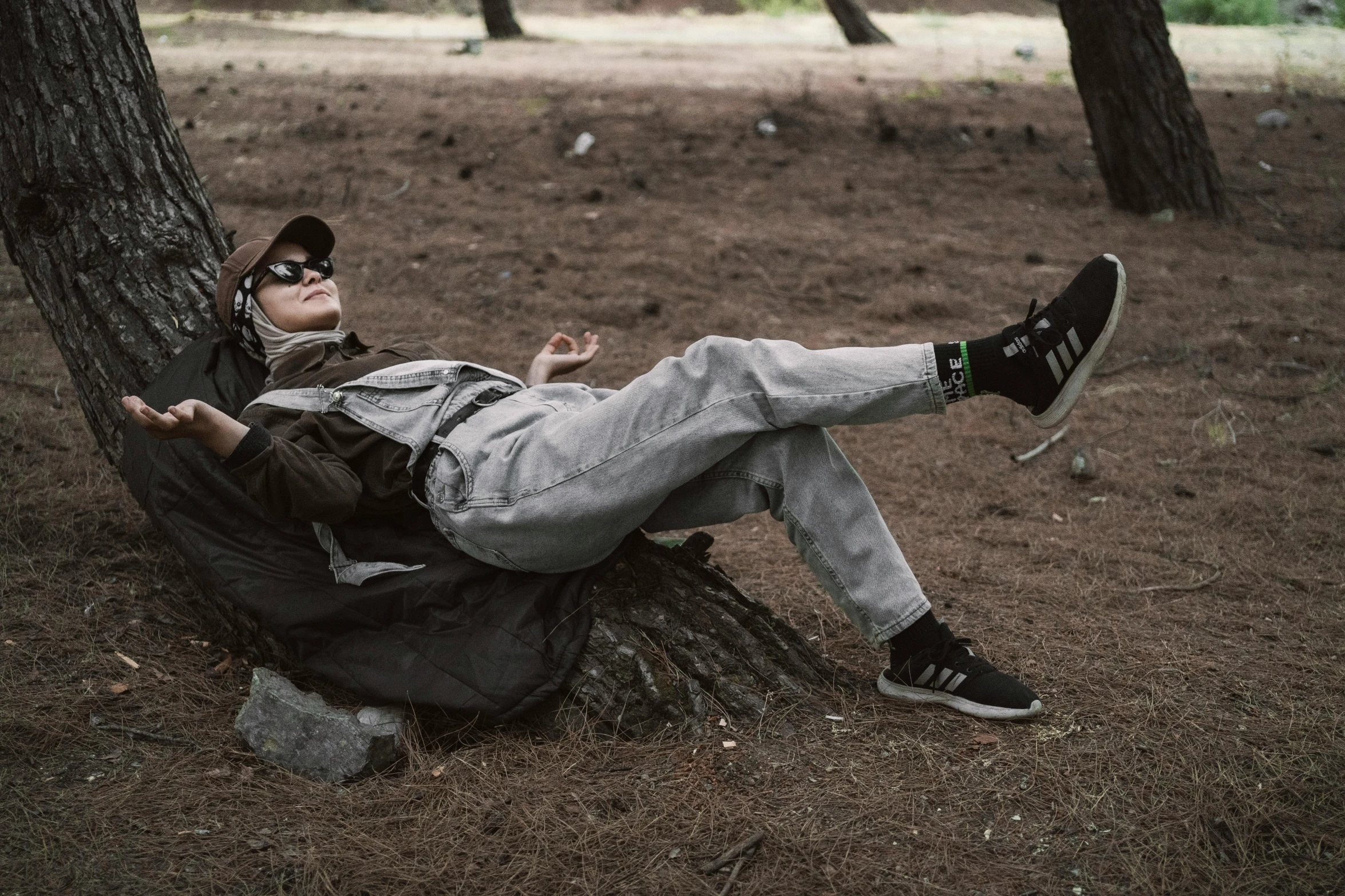 a young man lying against a tree wearing sunglasses