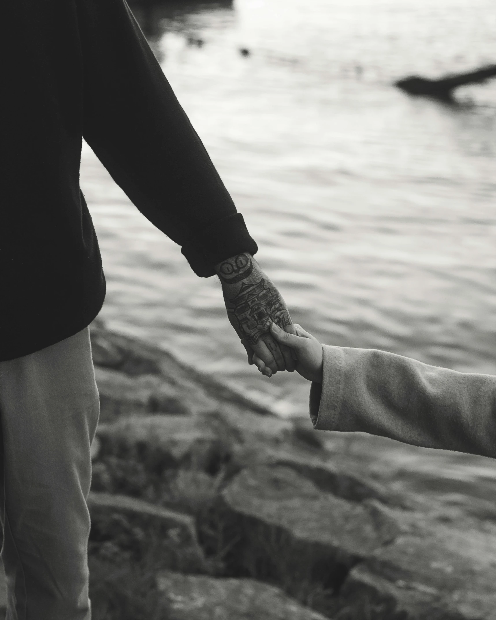 a person holds the hand of a child near water