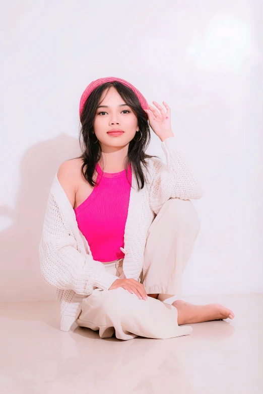 the asian woman sits cross legged in pink on a white background