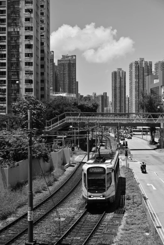 black and white image of a train traveling on a city street