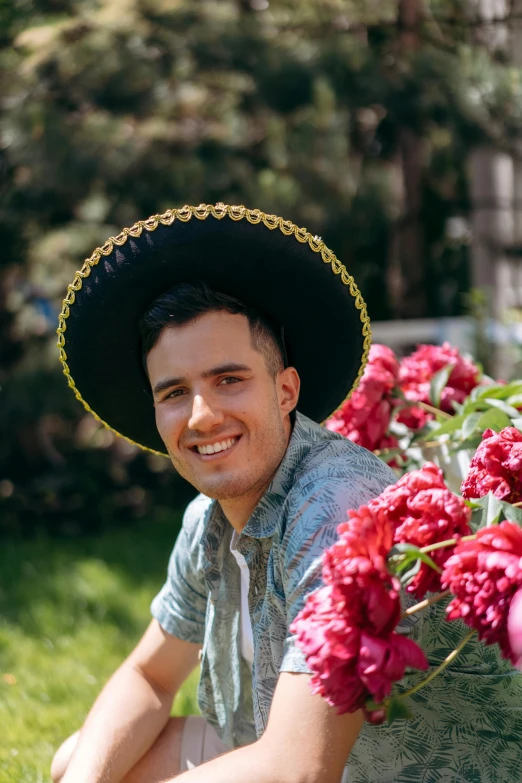 a man in a sombrero sits near some flowers