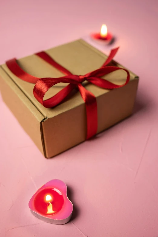 a lit candle inside a box with a ribbon