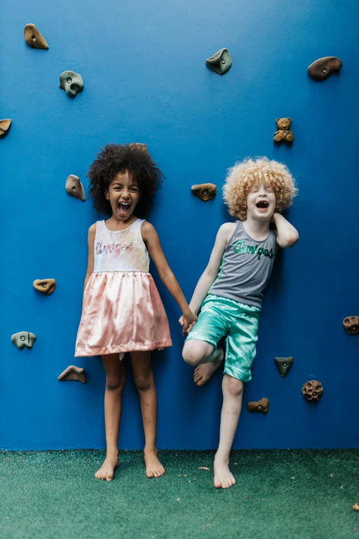 two small children posing for a po, with climbing walls behind them