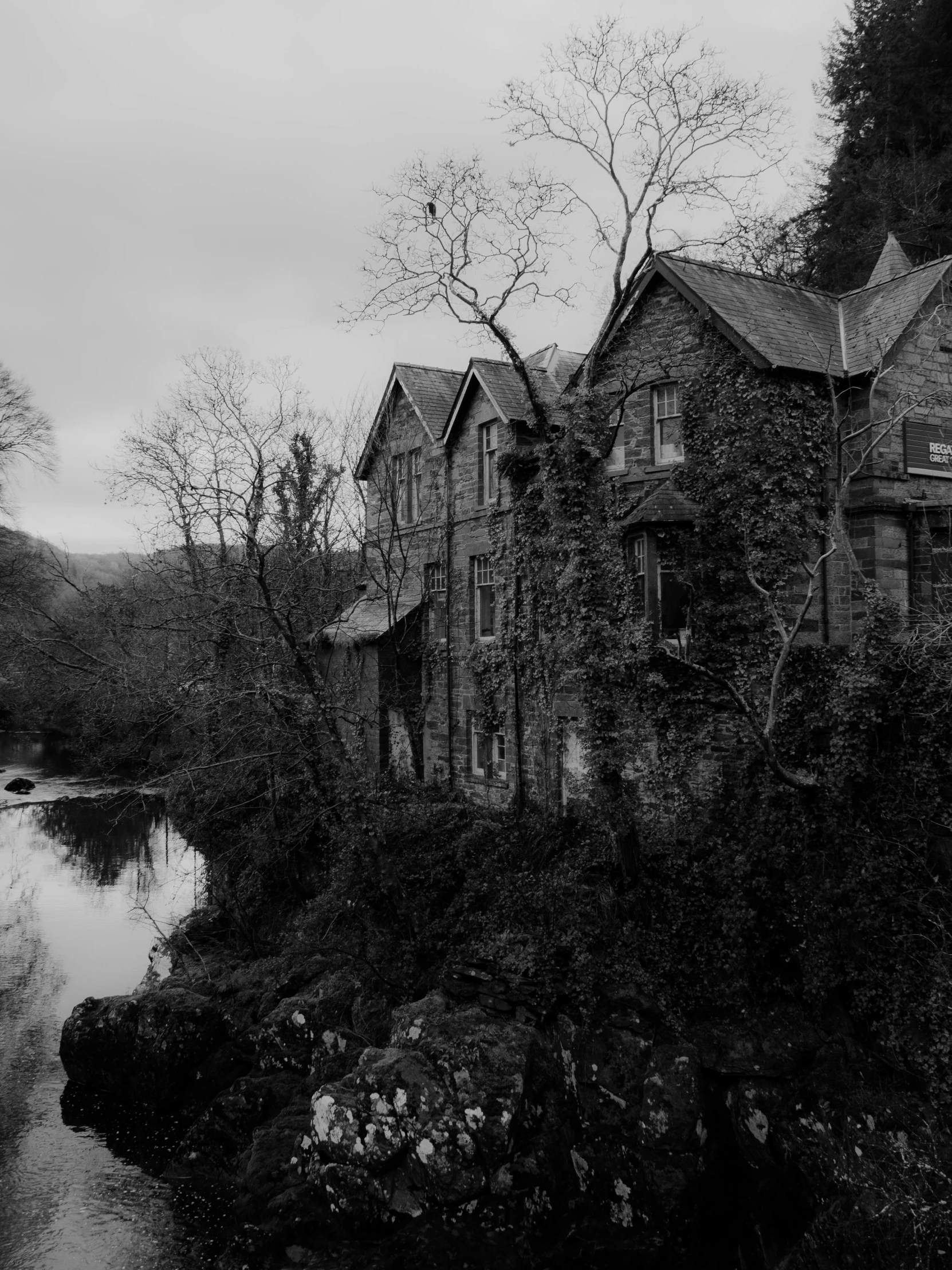 black and white po of an abandoned home by a stream