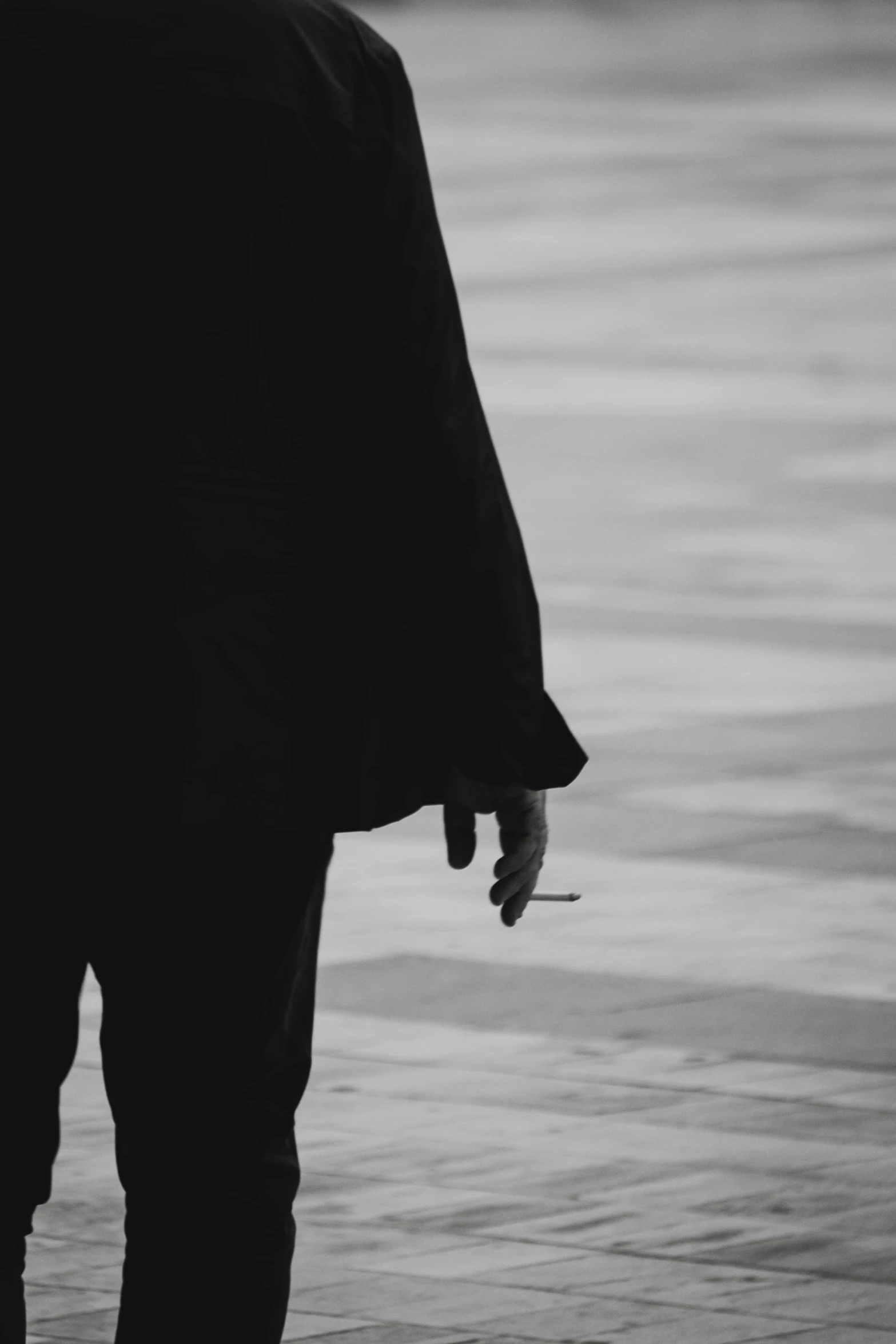 a man is walking down a street with a cigarette in his hand