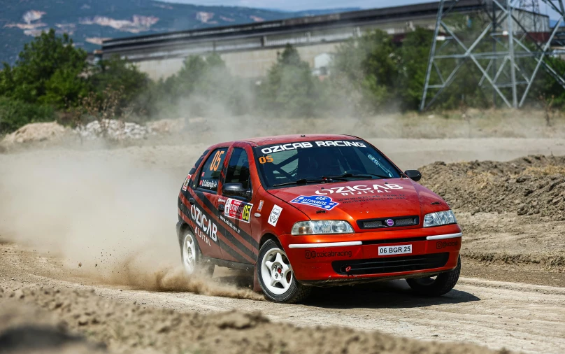 the red car is driving on a dirt track