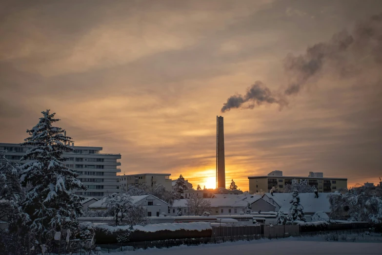 a winter sunrise on a snowy area with factories in the distance