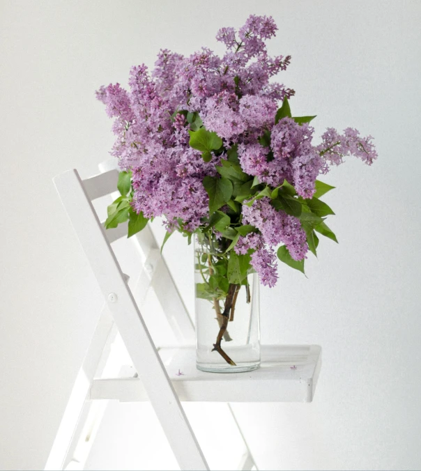 a vase of lavenders and greenery is in a chair