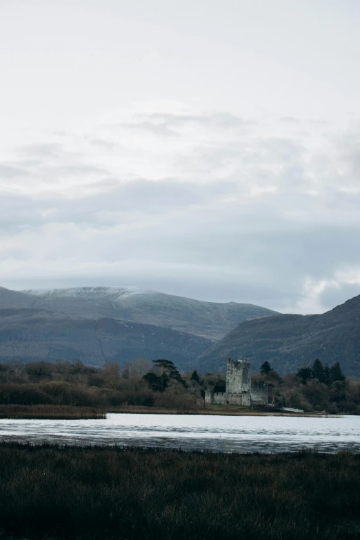 a castle stands near some mountains in the foreground