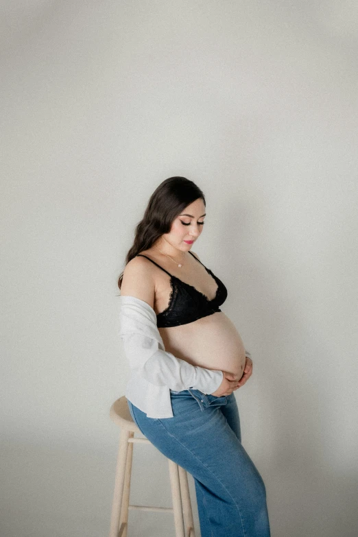 a pregnant woman in black top sitting on stool