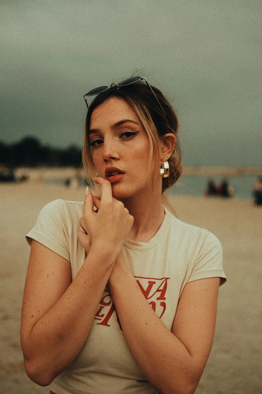 a young woman with tattoos stands on the beach