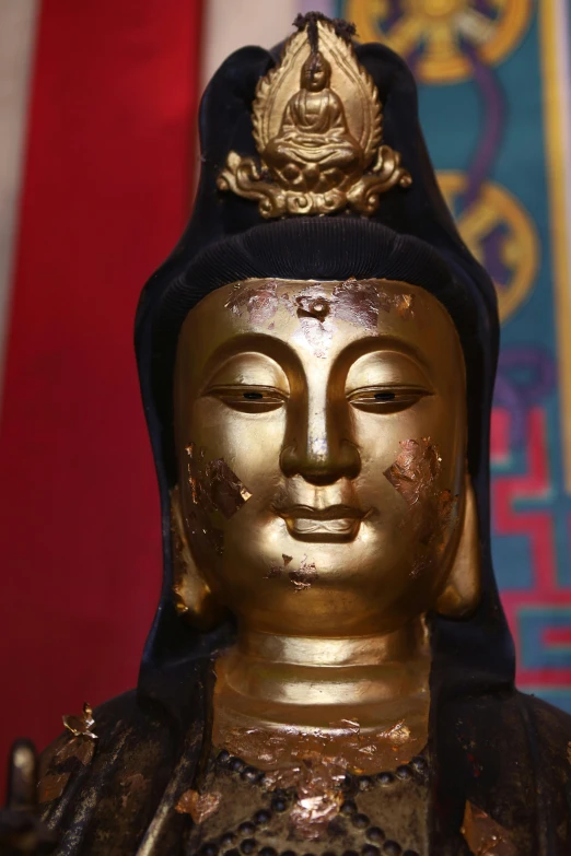 a buddha statue with a black hat and gold accents