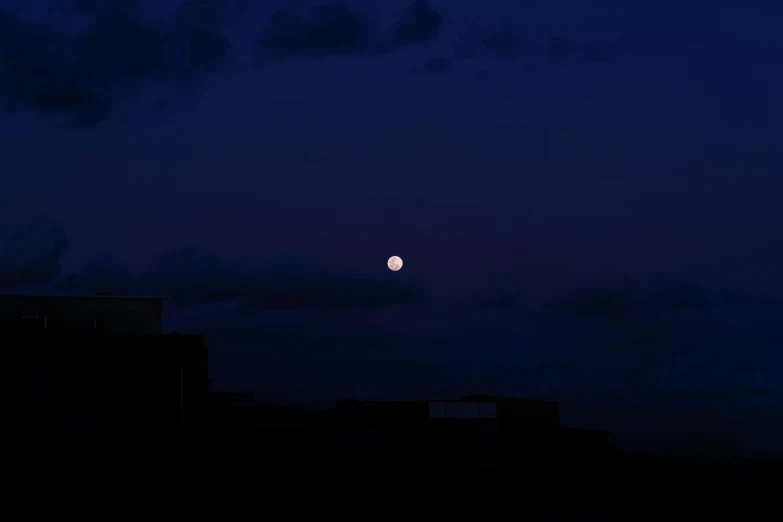 the moon is shining in the night sky above buildings