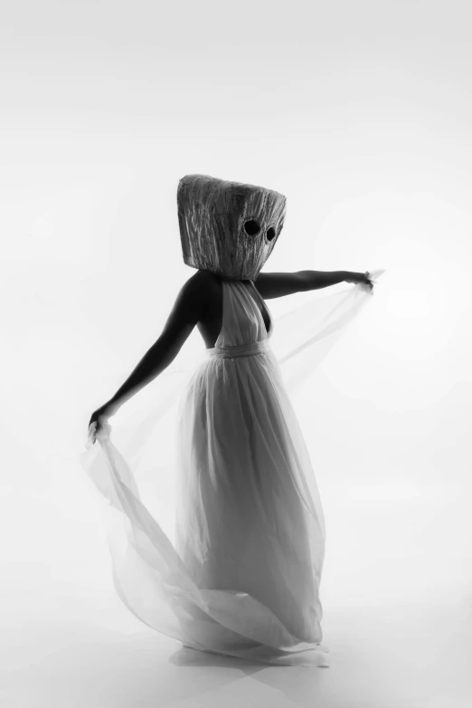 a woman in a dress stands in front of a white backdrop