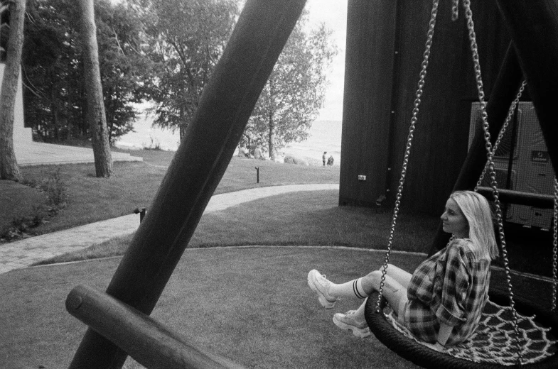 a  sitting on a swing in front of a tree