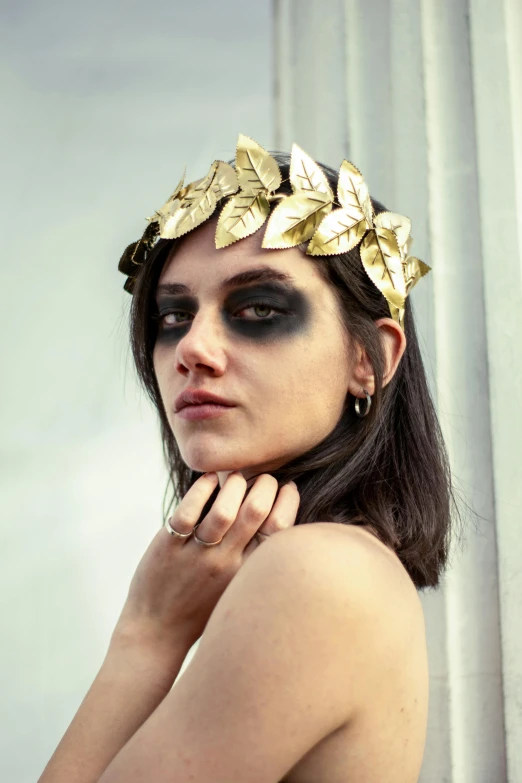 a woman with very large black lashes and gold leaf decorations