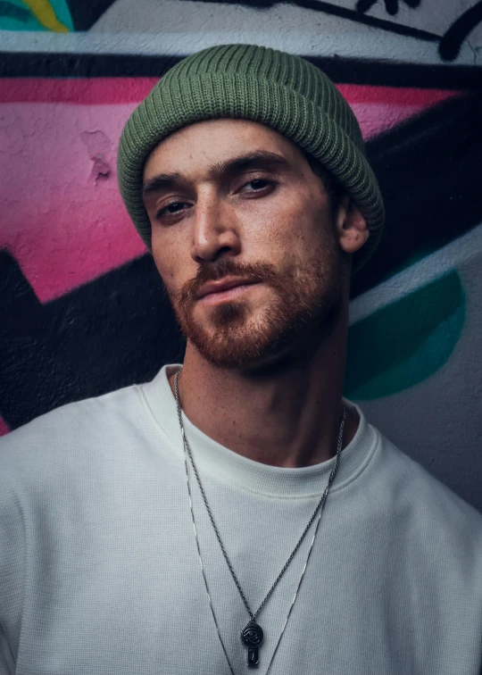 a young man poses for a picture in front of graffiti