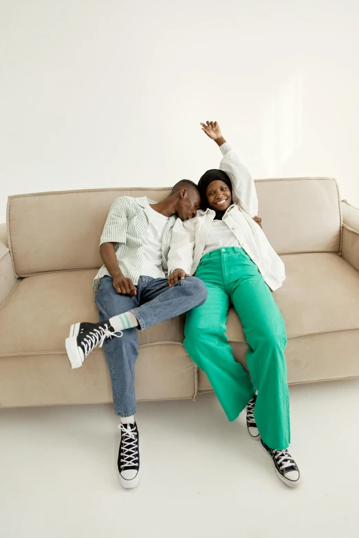 two people sitting on the couch, one holding his hand up