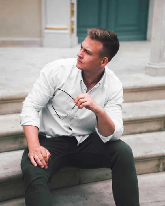 a man sitting on steps wearing a white shirt and black pants