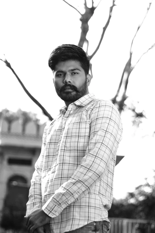 a man in plaid shirt standing next to a tree