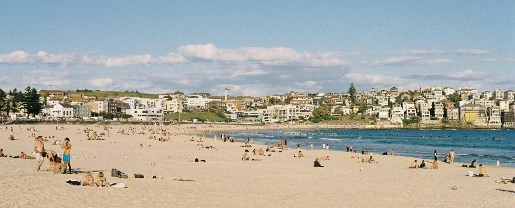 a beach with people walking and buildings in the background