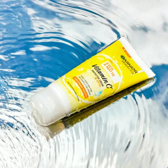 close up view of a tube of sunscreen water with splashing over the surface