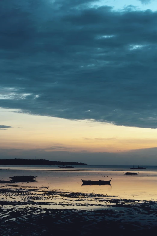 a boat is moored on the shore as the sun sets