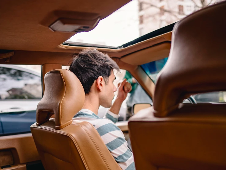 man in car sitting by rear window holding glasses