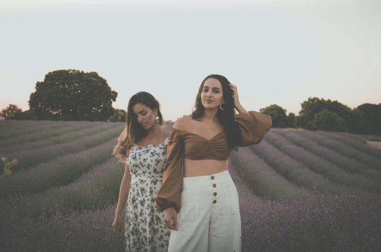 two girls are walking through a lavender field