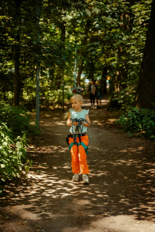 a girl is in the park carrying a blue and orange backpack