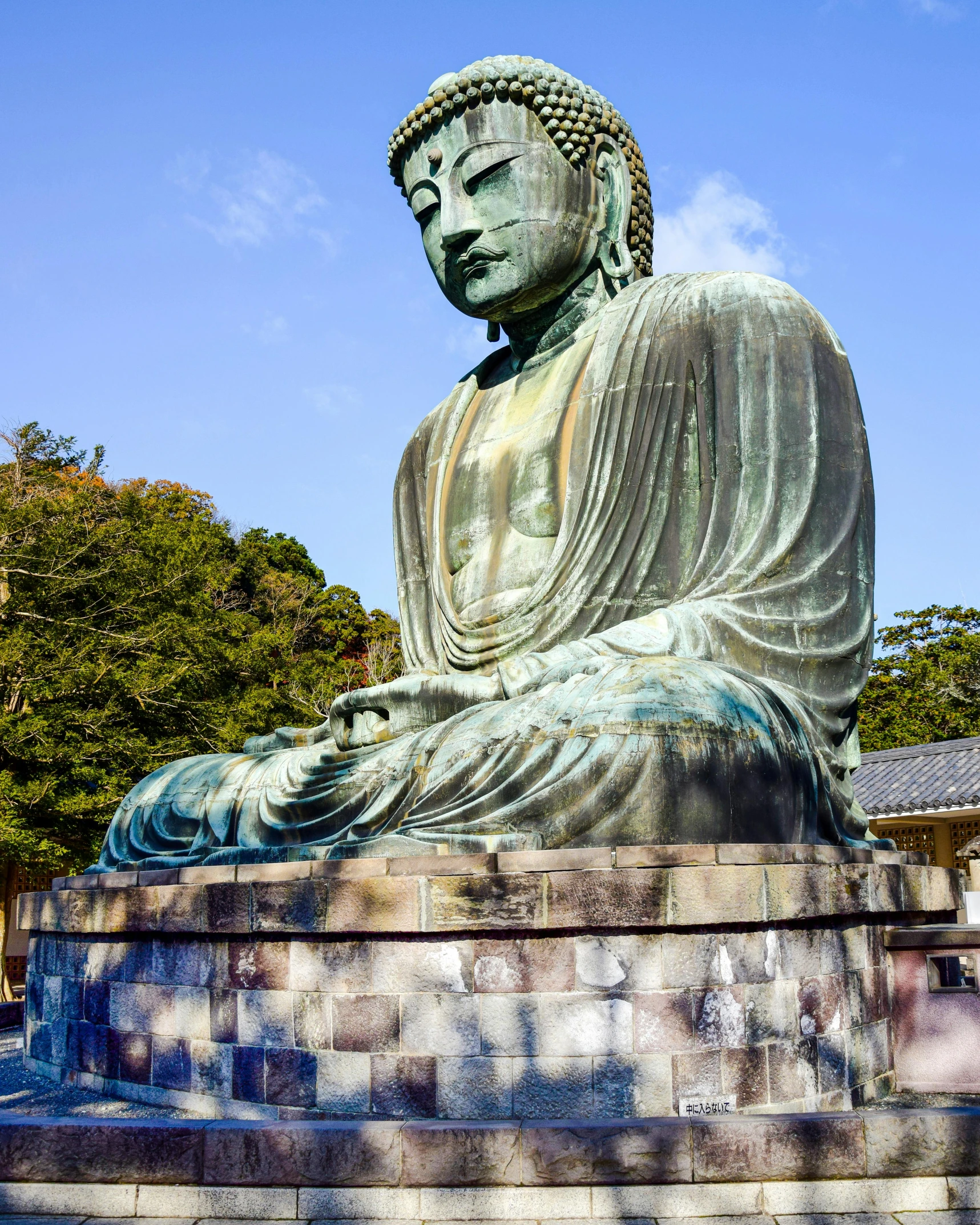 an old buddha statue sitting on a bench in the sun