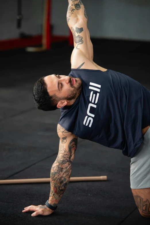 a man in blue shirt doing exercise with a bar