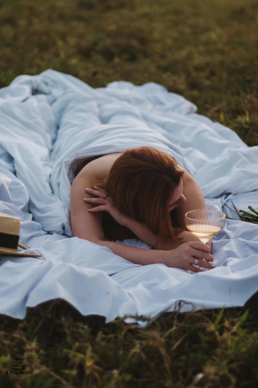 a woman lying on top of a grass covered field