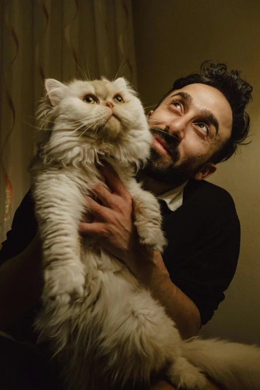 man holding cat in dark room with curtain