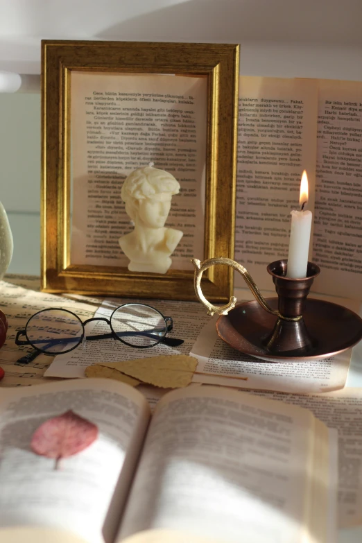 a candle is lit as an antique glass vase sits near books