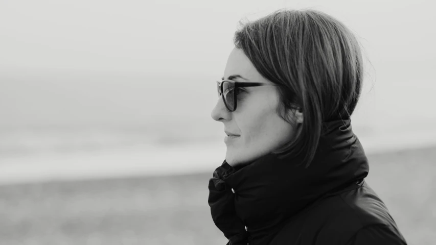 woman with black hair and sunglasses looking towards the water