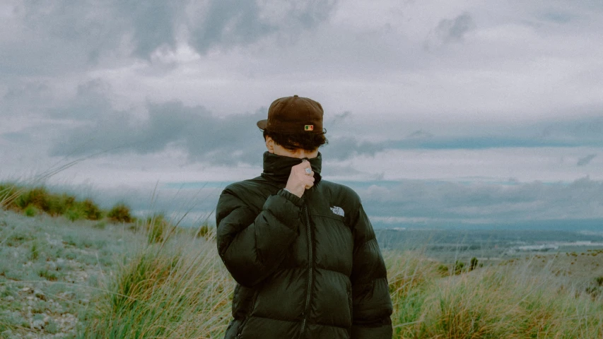 a man is standing on the top of a hill with an overcast sky