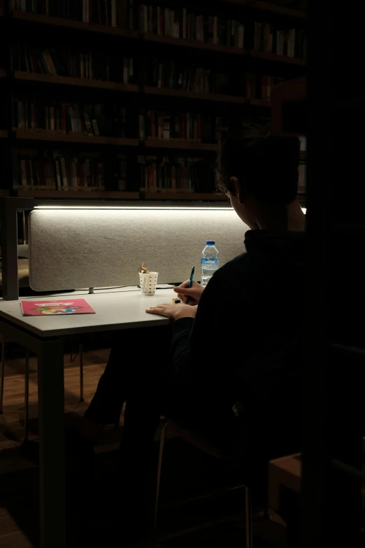 person sitting in a dark room writing with a laptop computer