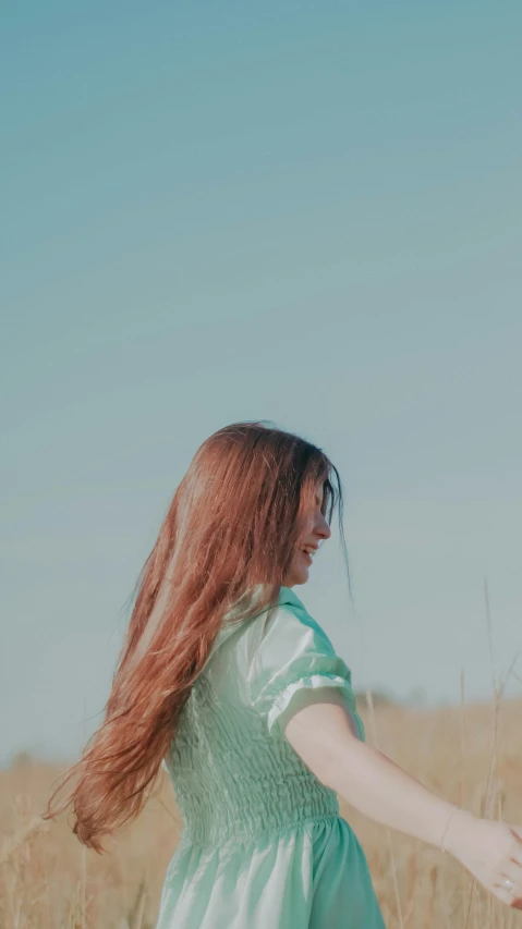 a woman stands in a field holding her arms out