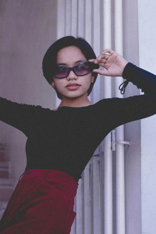 a woman posing with her arms outstretched while wearing a pair of sunglasses