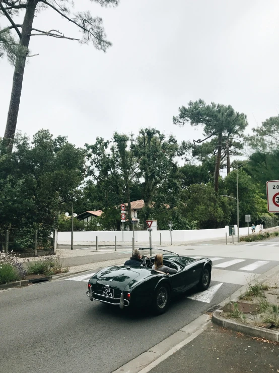 an older model sports car is at the cross walk