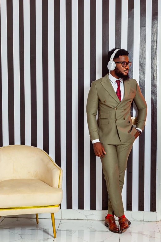 man in suit and tie leaning against wall with headphones on