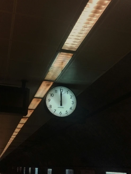 a large white clock sitting under some lights