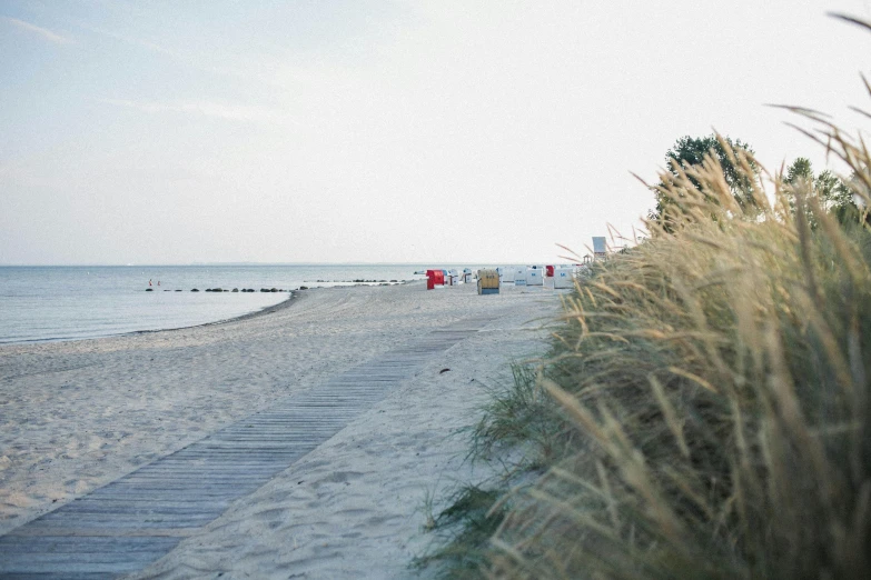 beach and boardwalk in daylight with people sitting on the beach