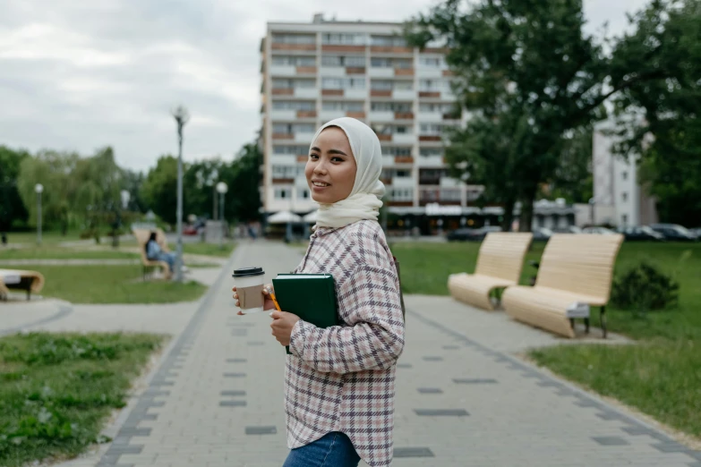 a woman in a headscarf walking across a park