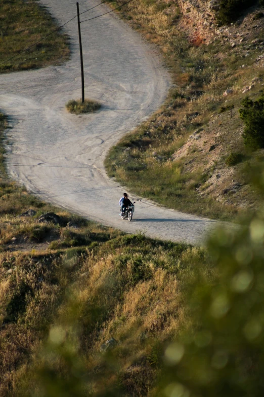 a person riding a motorcycle on a narrow road