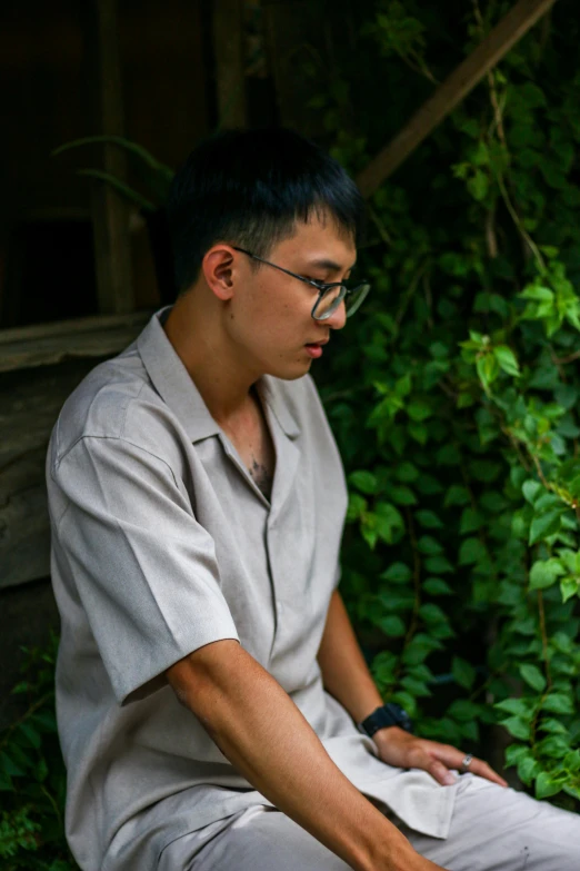 a man in glasses looking down sitting on the ground