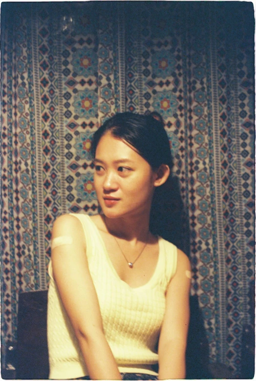 woman sitting against wall with beaded background looking at camera